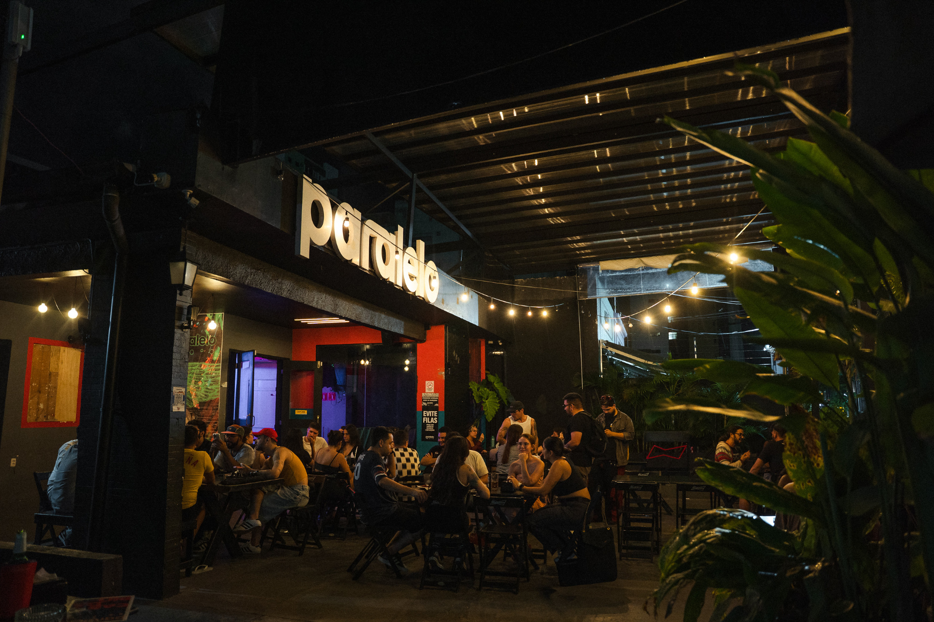 Fachada do bar Paralelo à noite com clientes nas mesas externas